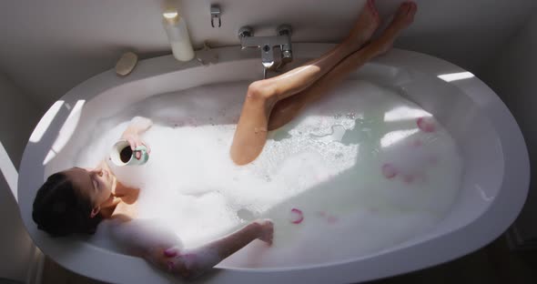 Woman drinking coffee while relaxing in a bathtub alt
