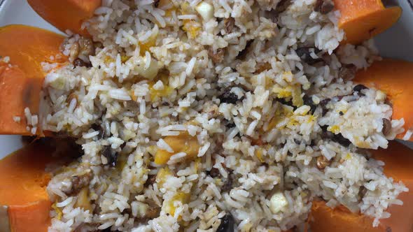 Stuffed roasted pumpkin, baked with a filling close-up on a plate, rotates alt