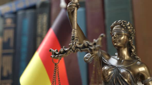 Statue of Lady Justice with Bookshelf with Books and Germany Flag Background alt
