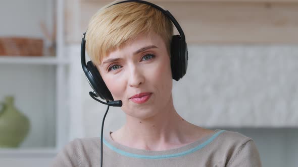 Millennial Woman in Headphones Looks at Camera Talking By Videoconference with Colleagues alt