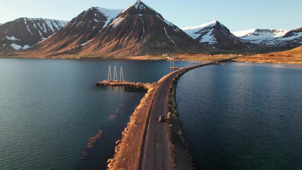 Drone Of Car Driving On Road Over Fjords Towards Mountains alt