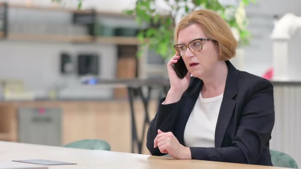Angry Businesswoman Talking on Smartphone in Office alt