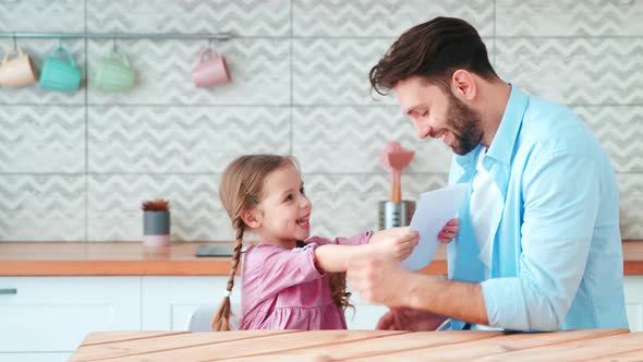 Little smiling girl giving a handmade card her father alt
