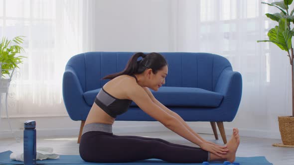 Athletic Healthy Asian woman in sportswear workout yoga sitting forward fold pose excercise on yoga alt