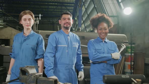 Multiracial workers collaborate and express happy work in a mechanical factory. alt