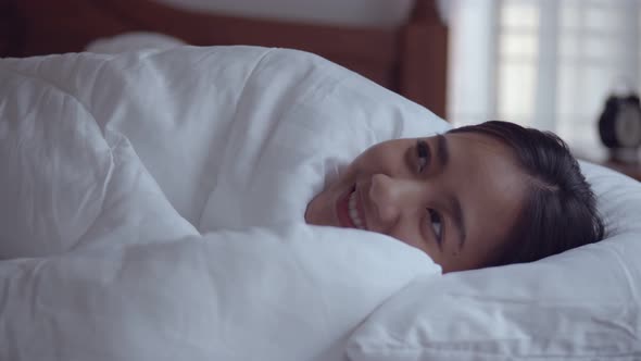 Young Asian woman waking up in the morning in a bedroom at home.