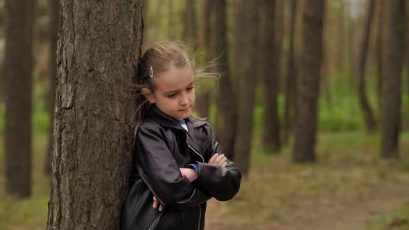 A Sad Angry Little Girl Standing in Front of a Tree in the Forest