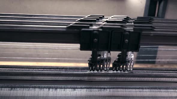 Close up shot of the weaving mechanism in a weaving machine.