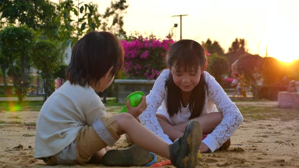 Asian Children Playing Sand In Playground Under Sunset alt