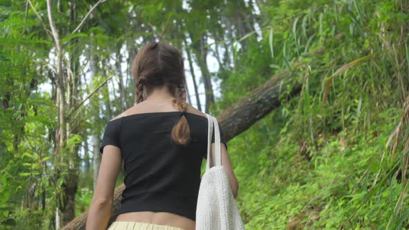 Lady Walks Up Old Brown Stairs Between Green Bushes alt