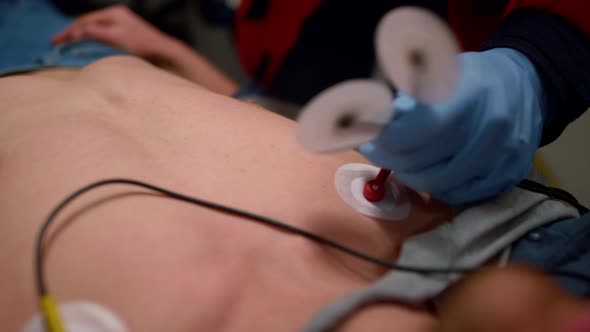 Emergency Doctor Hands Applying Sensors to Measure Man ECG alt