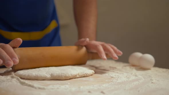 Man Rolls Out the Dough on the Kitchen Table.