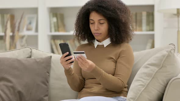 Online Payment Loss on Smartphone By Young African Woman on Sofa alt