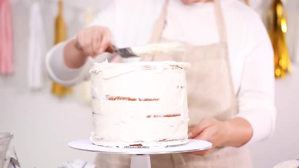 Step by step. Pastry chef stacking cake layers with buttercream frosting between to create unicorn c alt
