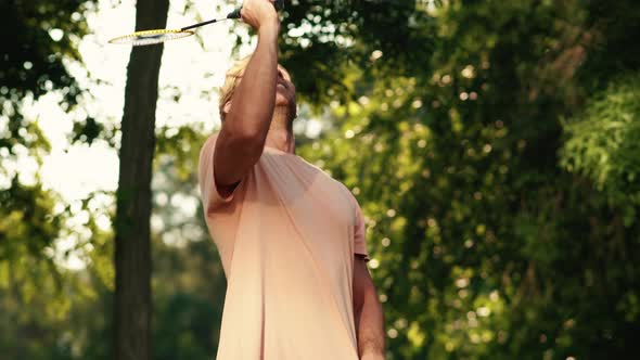 A pleased man is teaching his son playing badminton alt