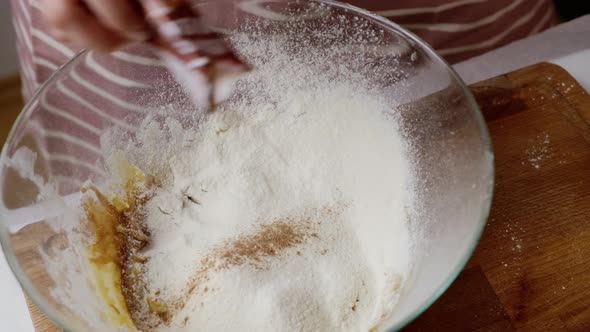 Woman Adds Cinnamon to Glass Bowl with Dough Ingredients alt