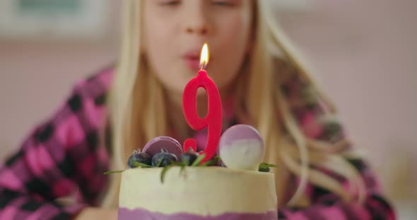 Close Up of Little Girl Blowing Out Red Candle with Number 9 on Birthday Cake in Slow Motion. Nine alt