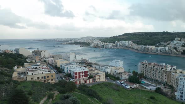 AERIAL: Flying Above Mellieha Bay with Houses and Harbour in Background