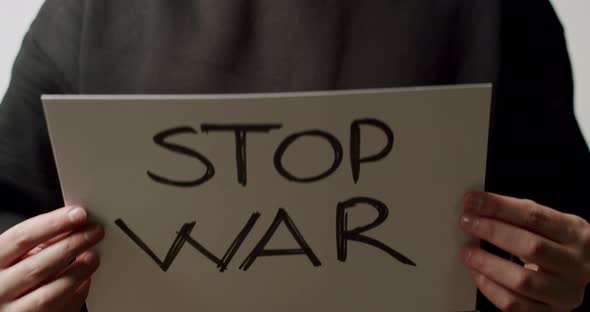Person Holding a White Paper with a Message No War alt