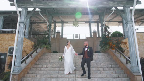 Handsome man leads his bride down the steps of a Japanese-style building