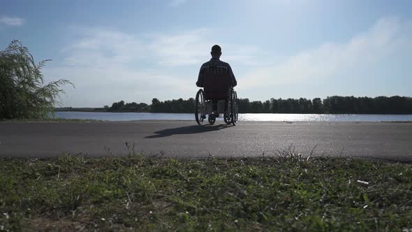 A Man in a Wheelchair Walks on the Waterfront