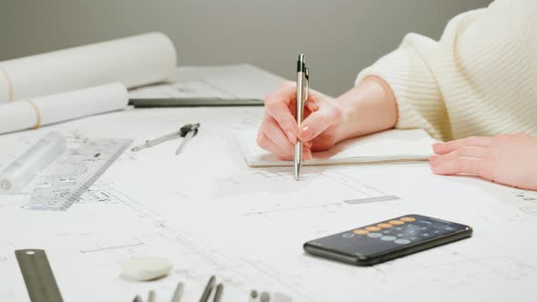 Architect Designer Counting on a Calculator Drawing Plan Blueprint Closeup alt