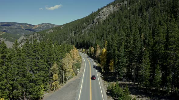 Aerial over mountain forest highway as cars pass below, Landscape Outdoor, 4K alt