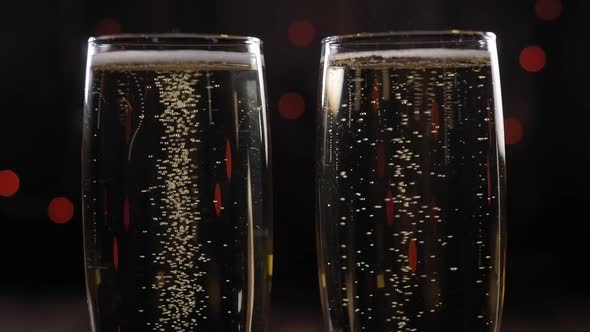 Two Glasses of Sparkling Wine on a Black Background with Blurred Flashing Lights alt