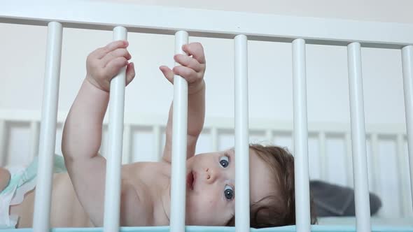little baby boy hands touching on the railing in the bed