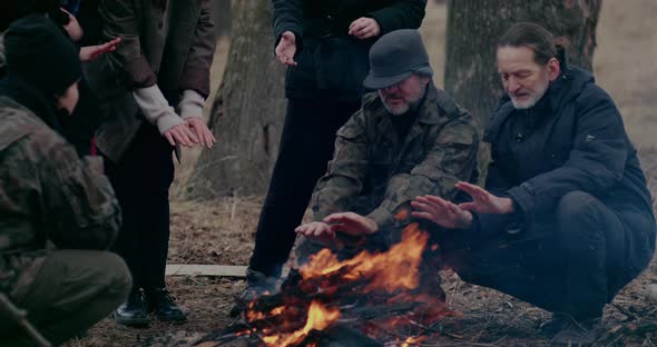 Soldier And Refugees Warming At Bonfire During Crisis alt