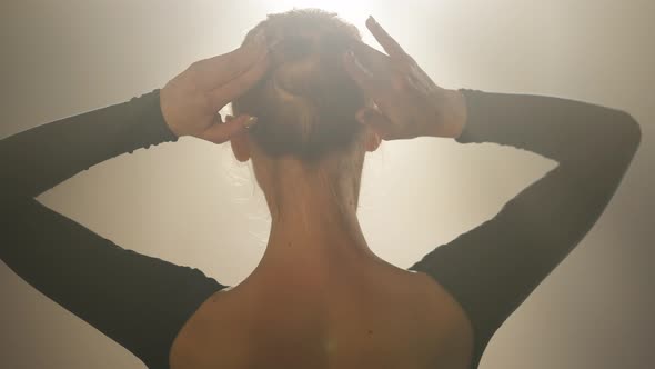 Back View of Slim Young Confident Woman Adjusting Bun Pigtail in Spotlight and Turning to Camera in alt