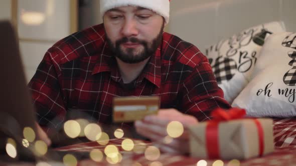 Man in Red Plaid Flannel Shirt in Santa Hat Shopping Online for Christmas