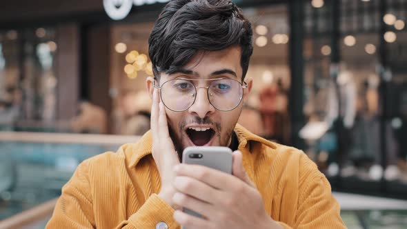 Young Guy Looking At Smartphone Screen Reading Email With Great News