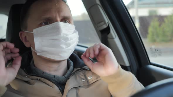 The Driver of the Car Puts on a Medical Mask