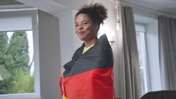 Joyful African American Smiling Woman Wrapping in German Flag Looking Away alt