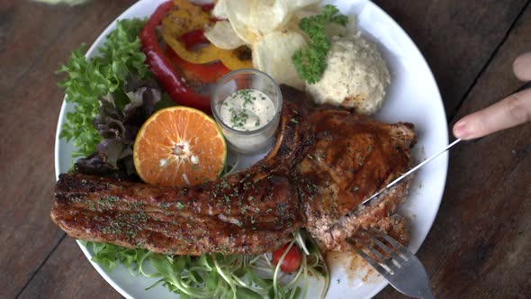 Cutting Pork T Bone With Knife And Fork Meat Fat Bone Steak With Salad And Mashed Potato Top View