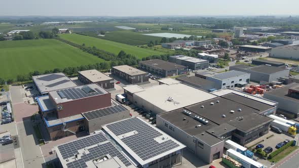 Aerial of small industrial terrain with solar panels on buildings rooftops - drone flying backwards alt