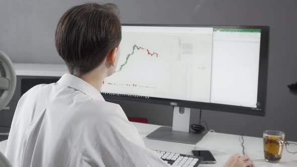 Female Stock Trader Smiling To the Camera While Working on Her Computer alt