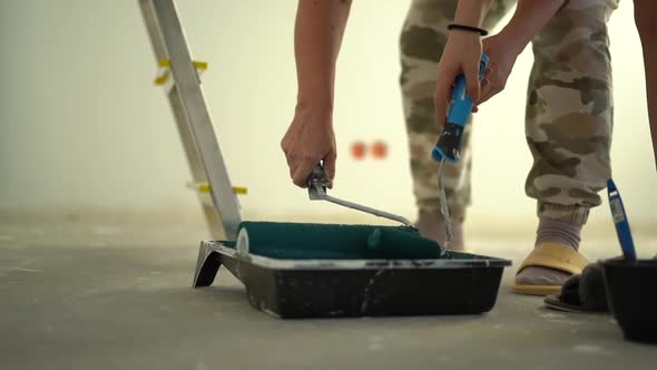 Unrecognizable Workers Hand Mixes White Paint with Roller in Plastic Construction Pallet Prepares to alt