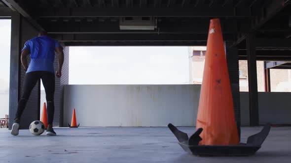 African american man doing tricks with a football in an empty urban building alt