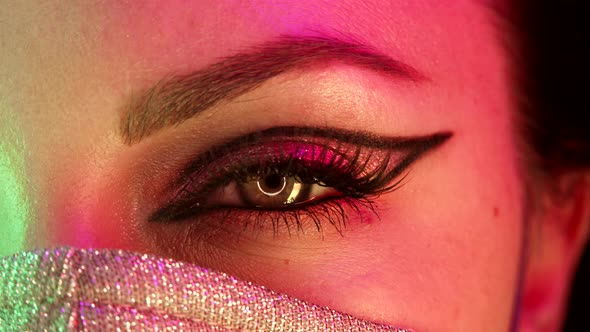 Woman Eye with Fancy Arrow Makeup Under Glowing Neon Light alt