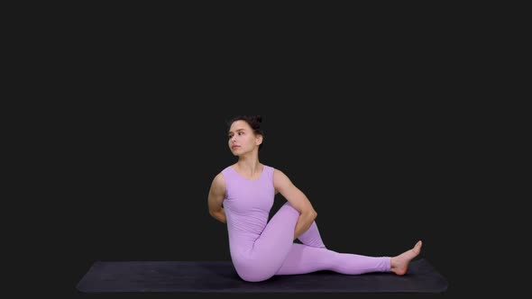 Young Sporty Woman Doing Half Spinal Twist Pose on Mat while Practicing Yoga, Alpha In