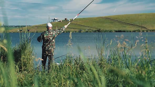 Fisherman Put a Line Out with a Fishing Pole Into the Lake alt