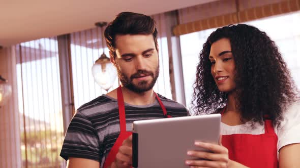 Smiling waiter and waitress using digital tablet alt