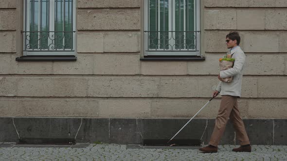 Person with Visual Impairment Carrying Grocery Bag Outdoors alt