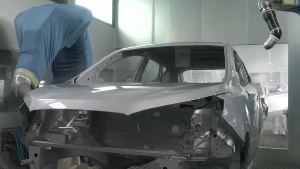 Robotic Arms Spray Painting a Vehicle Body at a Car Manufacturing Factory alt