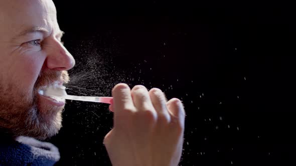 SLOW MOTION BACKLIT - A man brushing teeth sending many particles into the air alt