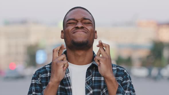 African American Man Stands in City Crossing Fingers Praying Says Prayer Hopes for Future alt
