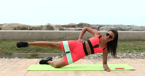 Sporty woman is planking outdoor during fitness session.