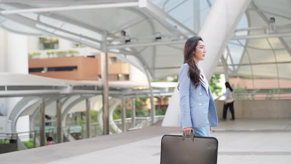 4K Asian business woman checking time on hand watch while walking in railway station in the morning. alt
